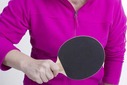 Active senior woman playing table tennis in front of white background