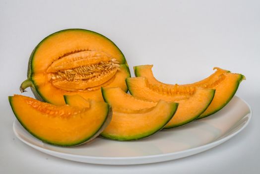 cut cantaloupe with slices on white background