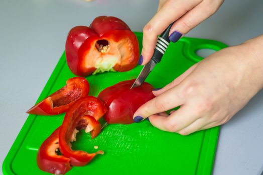 hand cut red bell pepper on green plastic board