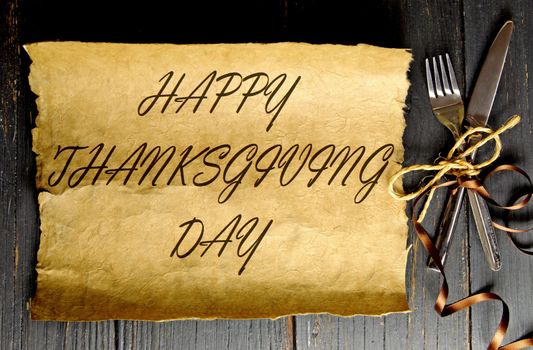 Fork and knife tied with satin ribbon with thanksgiving greeting on a paper scroll