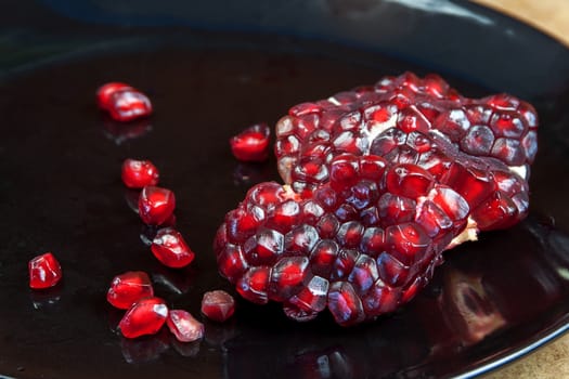 Carmine Pomegranate fruit cut dissect on black dish