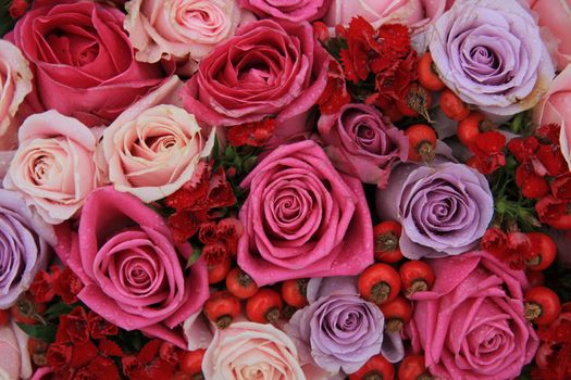 Bridal flower arrangement in various shades of pink and purple, mixed with red berries