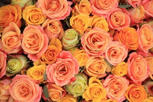 Yellow, orange and pink roses in a floral arrangement at a wedding