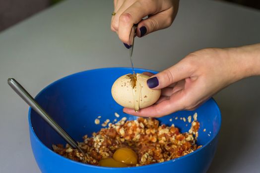 hand beats raw egg knife over a blue bowl