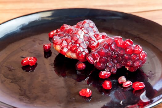 Carmine Pomegranate fruit cut dissect on black dish