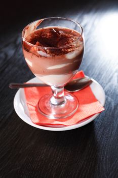 Cottage cheese mousse with chocolate in goblet on black table