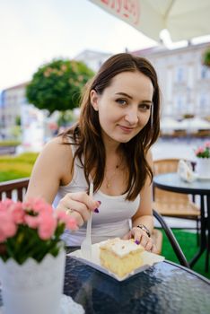 girl eating piece of fondant cake on table, outdoor restaurant