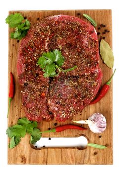 Marinated Raw Boneless Beef Shank with Herbs and Spices, Garlic and Chili Pepper closeup on Wooden Cutting Board on White background. Top View