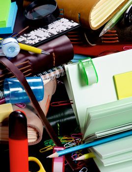 Background of Stationery Items with Notepads, Pens, Pencils, Paper Clips, Tape Dispenser, Sharpener, Stickers, Loop and Markers closeup