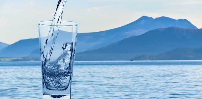 glass with water on background of mountains and lakes