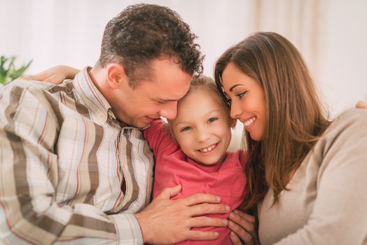 Beautiful young smiling family relaxing on sofa at living room.