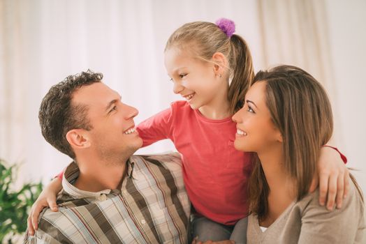 Beautiful young smiling family relaxing on sofa at living room.