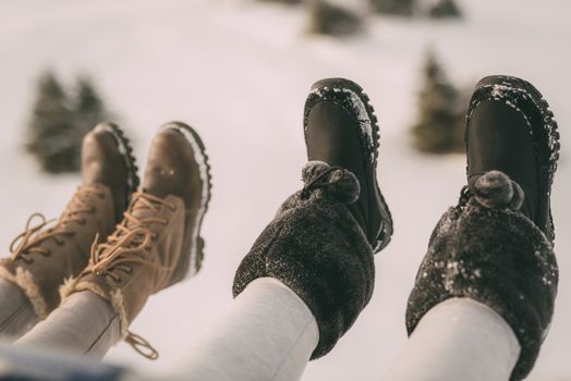 Close-up of a four unrecognizable female legs with boots on ski lift. Selective focus.