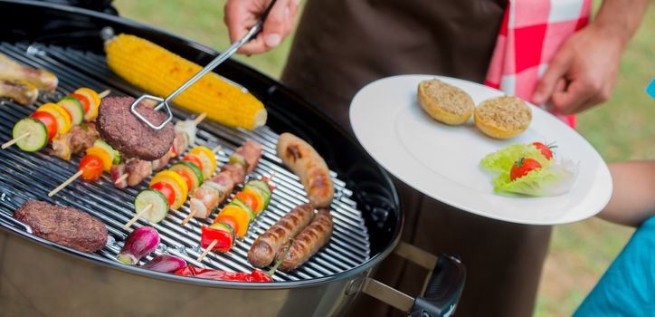 Service of meat on plate during a barbecue, France