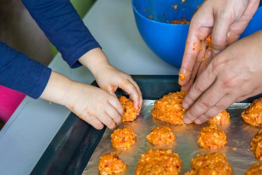 Children and dad hands put the meatballs on a baking sheet