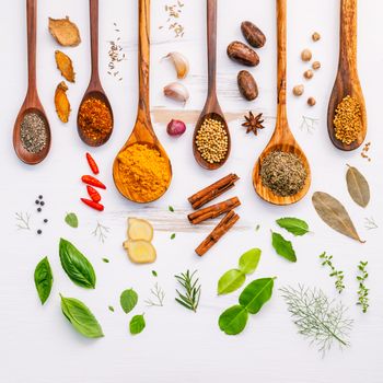 Various herbs and spices in wooden spoons. Flat lay of spices ingredients chilli ,pepper, garlic,dries thyme, cinnamon,star anise, nutmeg,rosemary, sweet basil and kaffir lime on wooden background.