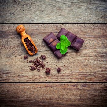 Chocolate background and dessert menu. Ingredients for bakery chocolate bar with mint ,chocolate powder in wooden spoon setup on dark shabby wooden background.