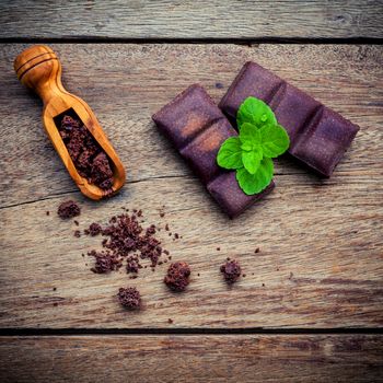Chocolate background and dessert menu. Ingredients for bakery chocolate bar with mint ,chocolate powder in wooden spoon setup on dark shabby wooden background.