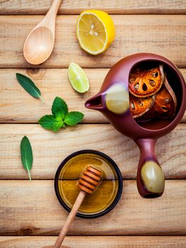 Herbal tea pot with fresh herbs sage ,peppermint ,dried indian bael, honey, lime and lemon on rustic wooden background flat lay.