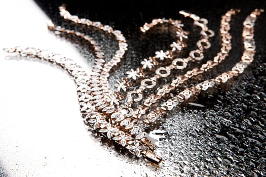 Golden bracelets on a black glass background with white highlight