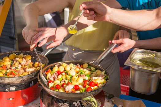 Cheff cooking traditional Mediterranean octopus with potatoes and vegetable on street stall on international street food festival of Odprta kuhna, Open kitchen event, in Ljubljana, Slovenia.