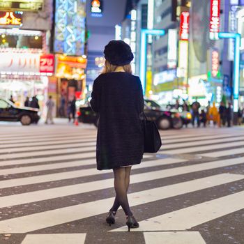 Solitary japanese woman waiting on crossroad in Kabukicho, entertainment and red-light district in Shinjuku, Tokyo, Japan.