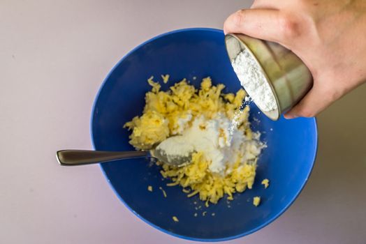 hand adds powdered sugar in butter over blue bowl