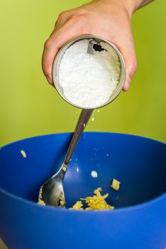 hand adds powdered sugar in butter over blue bowl