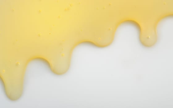 Honey liqiud flowing down on white background
