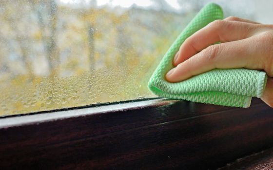 Woman cleaning water  condensation on window