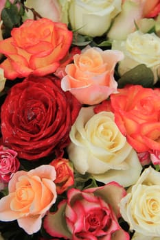 Roses in various shades of red, orange and pink in a bridal bouquet