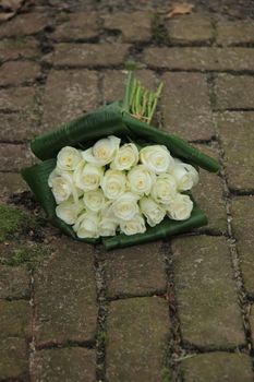 White sympathy roses in a small bouquet on the pavement