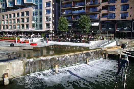 OSLO, NORWAY – AUGUST 17, 2016: People walking on wonderful modern residential district Aker Brygge with lux apartments, shopping, culture and restaurants in Oslo, Norway on August 17,2016.