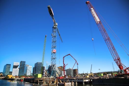 OSLO, NORWAY – AUGUST 17, 2016: A construction site of Bjorvika under construction in progress with a heavy vehicle and cranes in Oslo, Norway on August 17,2016.