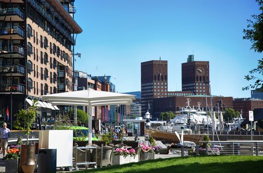 OSLO, NORWAY – AUGUST 17, 2016: People walking on modern district on street Stranden, Aker Brygge district with lux apartments, shopping, culture and restaurants in Oslo, Norway on August 17,2016.