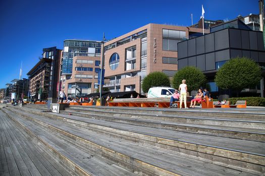 OSLO, NORWAY – AUGUST 17, 2016: People walking on modern district on street Stranden, Aker Brygge district with lux apartments, shopping, culture and restaurants in Oslo, Norway on August 17,2016.