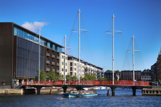 COPENHAGEN, DENMARK - AUGUST  16, 2016:  Beautiful view on the modern Circle Bridge ( Cirkelbroen ) and canal with tourist boat in Copenhagen, Denmark on August 16, 2016.
