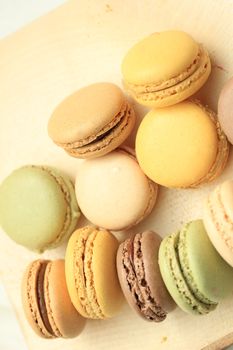 Macarons in different colors and flavors on a wooden cutboard