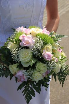 Bride holding her bridal bouquet, ivory roses and pink fresia