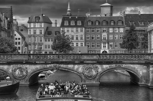 COPENHAGEN, DENMARK - AUGUST 14, 2016: Black and white photo, view of canal, boat with tourist and old bridge from bridge Prinsens Bro in Copenhagen, Denmark on August 14, 2016.