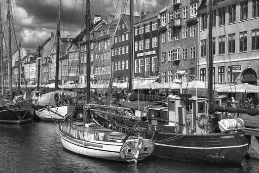 COPENHAGEN, DENMARK - AUGUST 14, 2016: Black and white photo, boats in the docks Nyhavn, people, and colorful architecture. Nyhavn a 17th century harbour in Copenhagen, Denmark on August 14, 2016.