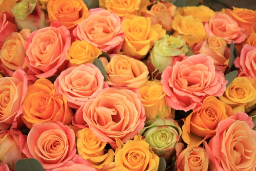 Yellow, orange and pink roses in a floral arrangement at a wedding