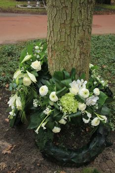 Sympathy wreaths near a tree on a cemetery