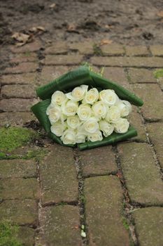 White sympathy roses in a small bouquet on the pavement