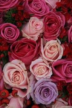 Bridal flower arrangement in various shades of pink and purple, mixed with red berries