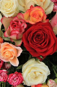 Roses in various shades of red, orange and pink in a bridal bouquet