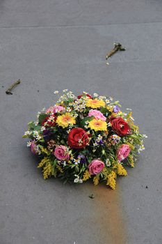 Multicolored sympathy flowers on a grey tombstone