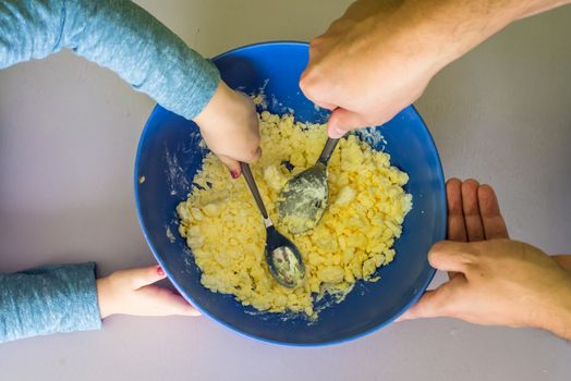 Children and dad hands preparing shortbread dough in blue bowl