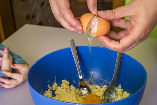 hand pours out raw egg of the shell in shortbread dough