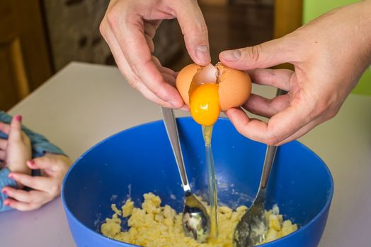 hand pours out raw egg of the shell in shortbread dough